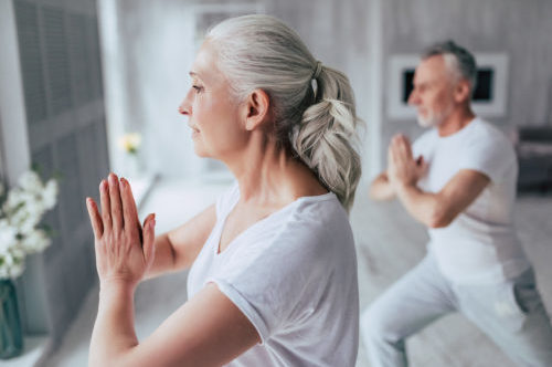 Senior couple is doing fitness training at home. Doing yoga together. Healthy lifestyle concept.